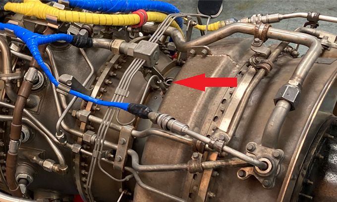 Red arrow pointing at the remote visual inspection access point in a GE CT7/T700 turbine engine for a helicopter